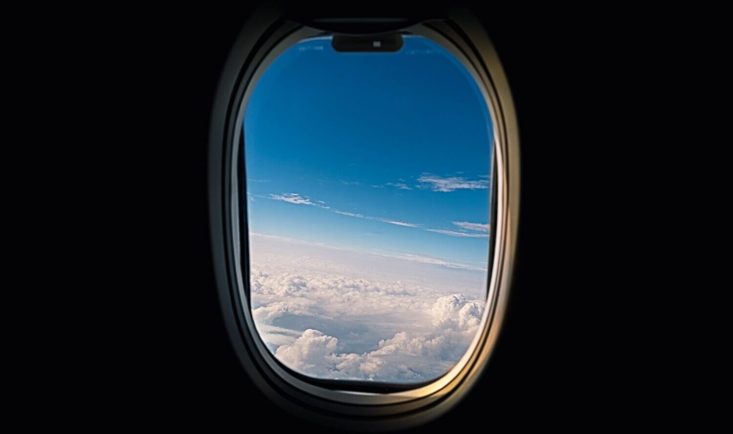 Looking Out A Jet Window to Blue Sky and White Clouds